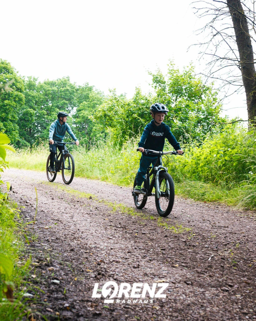 Kleiner Junge fährt mit den Fahrrad vor seinem Vater